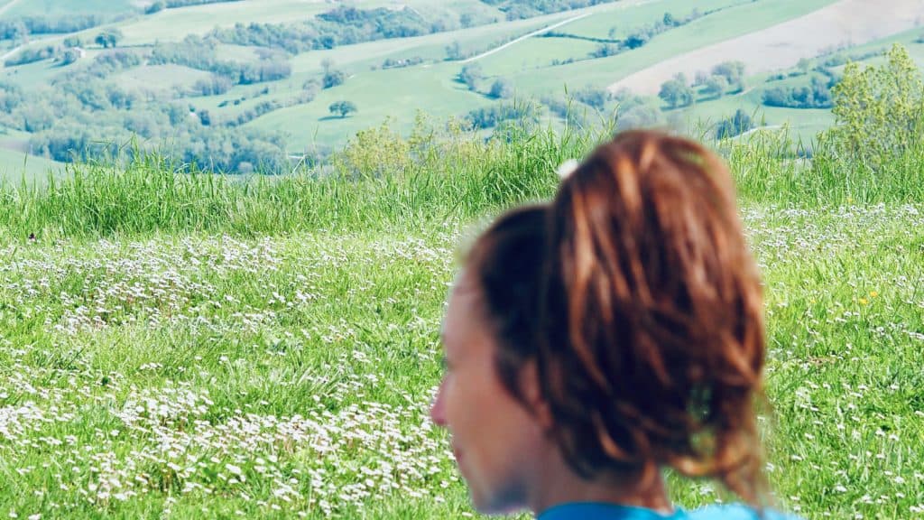 Frau schaut in die Weite von Hügeln mit Wiesen